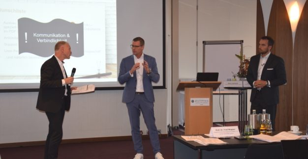 Zwei Männer in Anzughose und Hemd präsentieren vor einer Leinwand – vermutlich ein Vortrag oder Workshop.