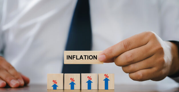 Mann hält Bauklotz mit den Worten "Inflation" in die Kamera