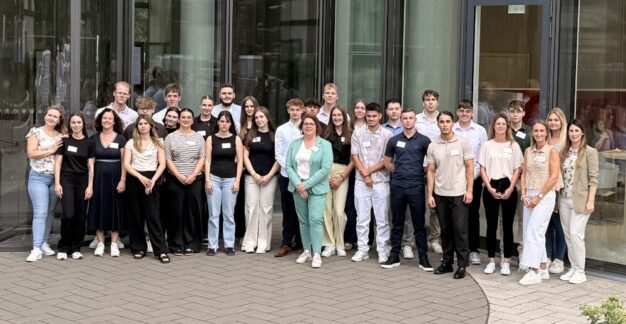 Ausbildungsstart 2025 bei MRH Trowe – Herzlich willkommen! Gruppenfoto einer vielfältigen Gruppe junger Berufseinsteigerinnen und Berufseinsteiger sowie Betreuender vor einem modernen Bürogebäude – aufgenommen anlässlich des Ausbildungsstarts 2025.