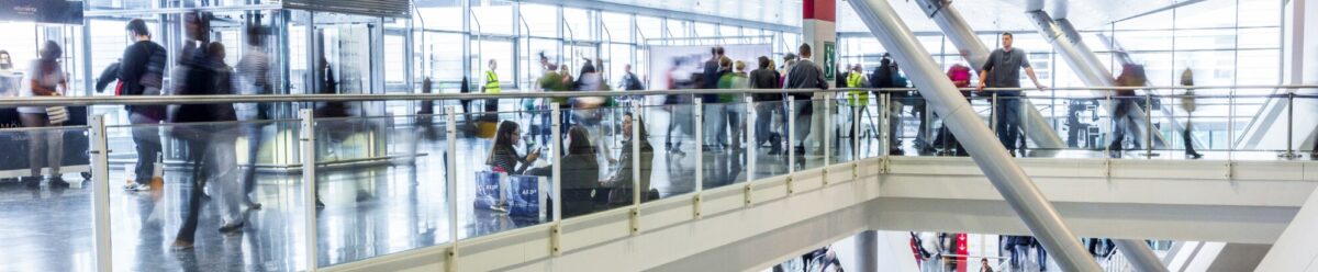 Menschen bewegen sich durch eine Messe- oder Ausstellungshalle – Symbolbild für Ausstellungsversicherung und Veranstaltungsschutz.