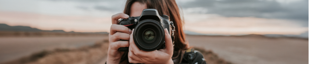Fotografin mit Kamera im Freien, Symbol für kreative Berufe und die Absicherung durch eine Berufshaftpflichtversicherung.