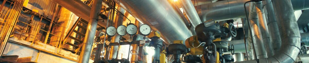 Komplexe Industrieanlage mit Rohrleitungen, Ventilen und Messgeräten, Sinnbild für Produktionsrisiken und die Absicherung durch eine industrielle Haftpflichtversicherung.