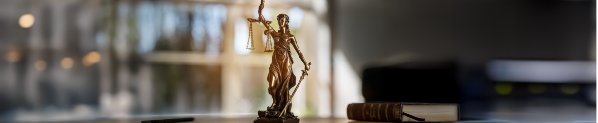 Justitia-Statue auf einem Schreibtisch – Symbolbild für Rechtsschutzversicherung und juristische Absicherung.