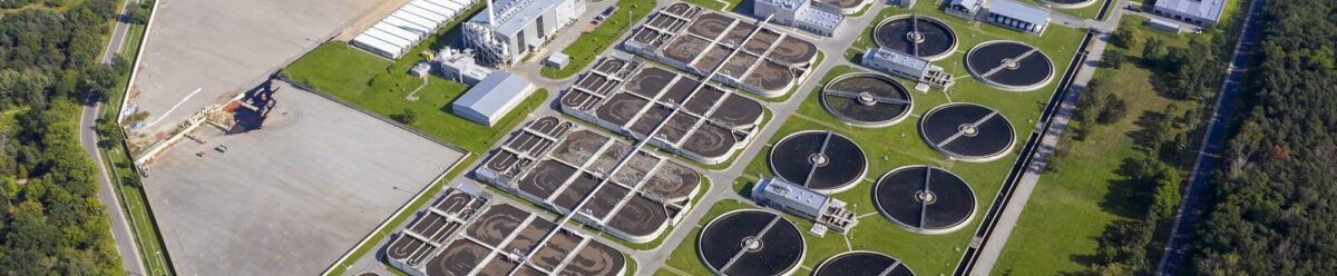 Luftaufnahme einer Kläranlage mit Becken und technischen Anlagen, Symbol für Umweltrisiken und die Absicherung durch eine Umweltschadenversicherung.