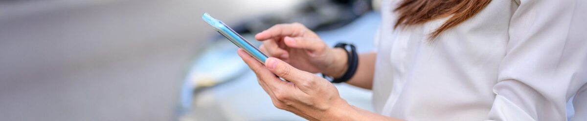 Person hält Smartphone im Auto – Symbolbild für Verkehrsrechtsschutz und rechtliche Absicherung im Straßenverkehr