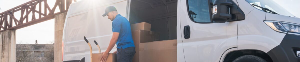 Lieferfahrer lädt Kartons mit einer Sackkarre aus einem Transporter – Symbolbild für Verkehrshaftungsversicherung und Speditionsrisiken.