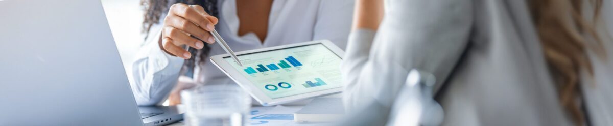 Beraterin erklärt einer Kundin Finanzdiagramme auf einem Tablet, Symbol für Beratung, Risikoanalyse und individuelle Versicherungslösungen.