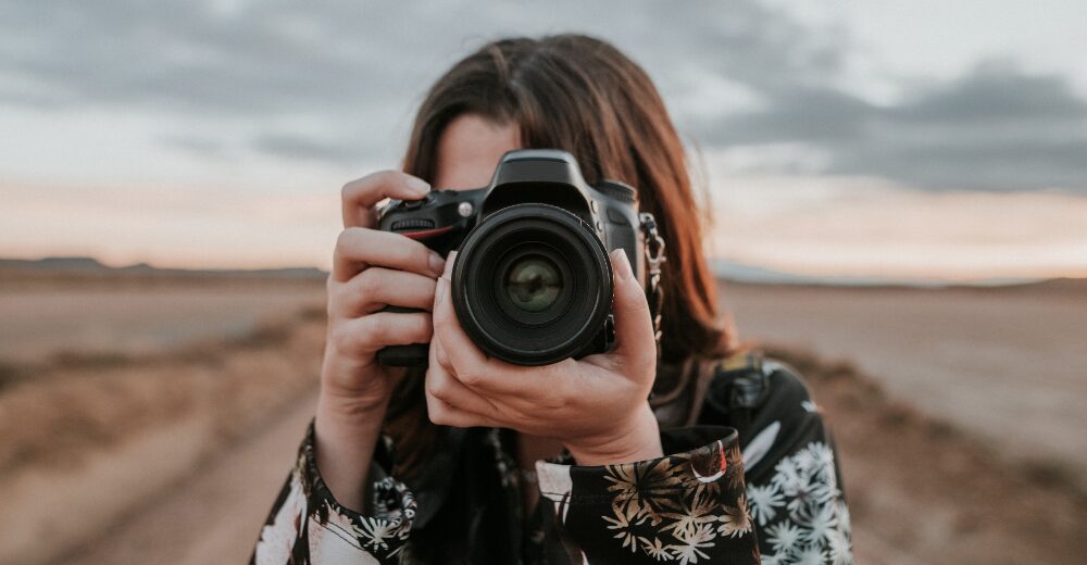 Fotografin mit Kamera im Freien, Symbol für kreative Berufe und die Absicherung durch eine Berufshaftpflichtversicherung.