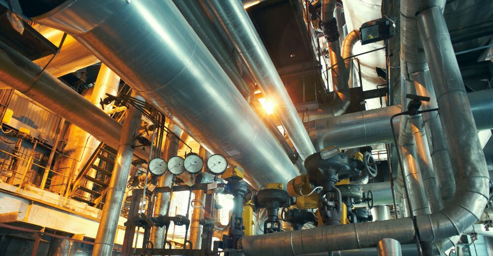 Komplexe Industrieanlage mit Rohrleitungen, Ventilen und Messgeräten, Sinnbild für Produktionsrisiken und die Absicherung durch eine industrielle Haftpflichtversicherung.