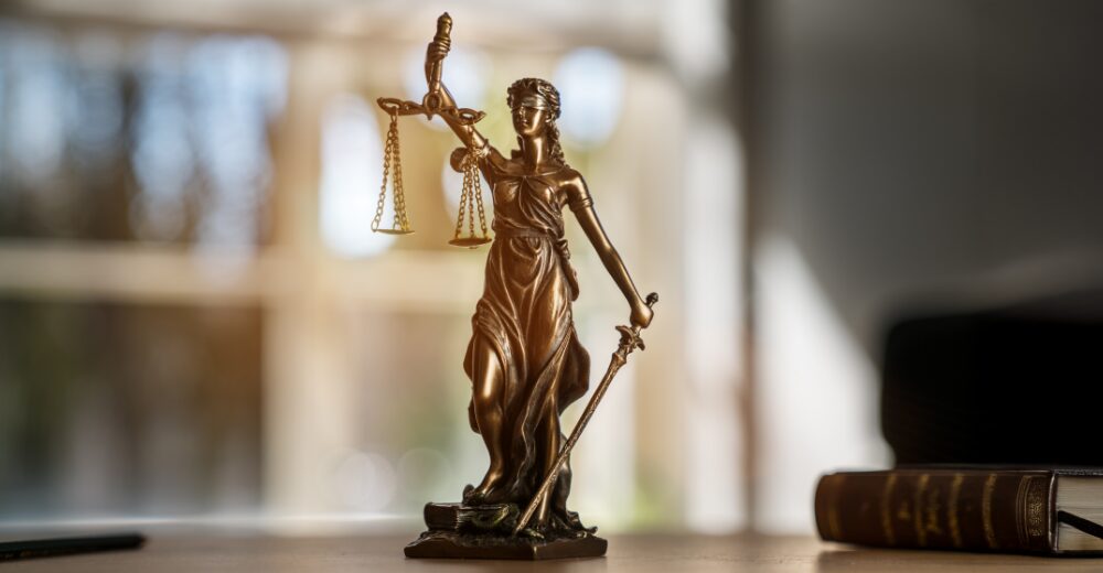 Justitia-Statue auf einem Schreibtisch – Symbolbild für Rechtsschutzversicherung und juristische Absicherung.