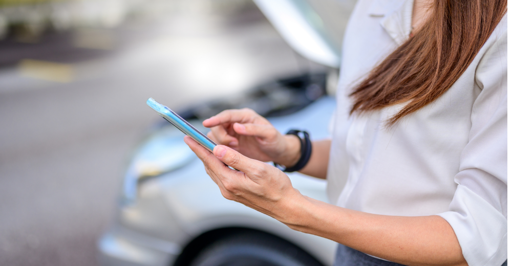 Person hält Smartphone im Auto – Symbolbild für Verkehrsrechtsschutz und rechtliche Absicherung im Straßenverkehr.