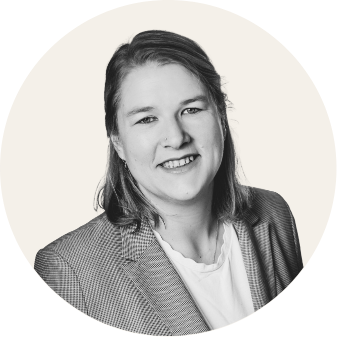 Porträt eines lächelnden Mannes im Anzug vor neutralem Hintergrund, schwarz-weiß.