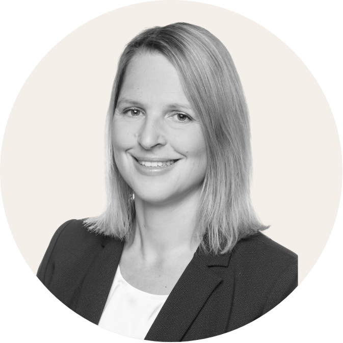 Porträt eines lächelnden Mannes im Anzug vor neutralem Hintergrund, schwarz-weiß.