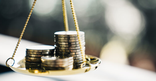 Waage mit gestapelten Münzen als Symbol für faire und ausgewogene Vergütung.